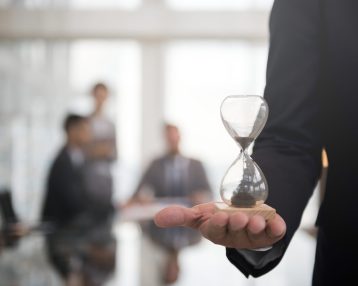 Businessman holding an hour glass, signifies the importance of being on time
