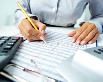 Photo of human hands holding pencil and ticking data in documents
