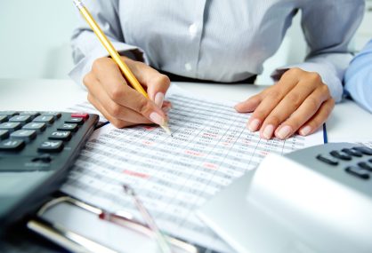Photo of human hands holding pencil and ticking data in documents